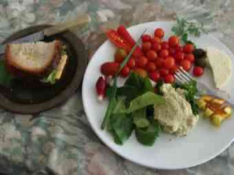 A salad lunch with hummus and a honey sandwich on the side. A salad lunch with hummus and a honey sandwich on the side.