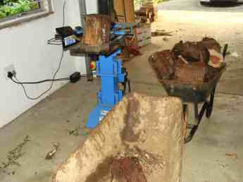 A commercial firewood splitter shown together with a pile of logs.